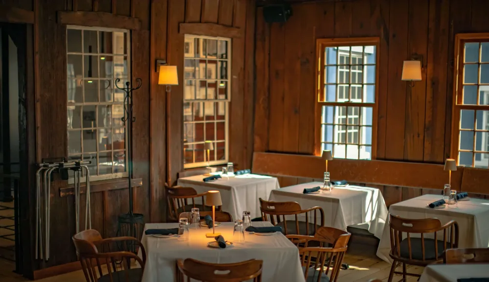 A welcoming dining room at The Brushmill by the Waterfall, with timber beams and tables set for guests